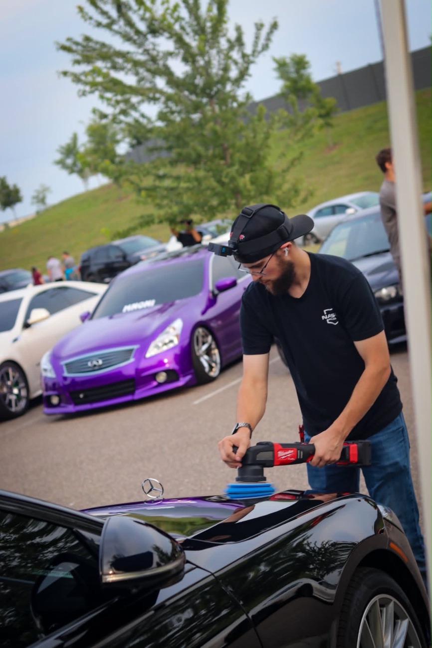 Leonard of L&Y Detailing machine-polishing the hood of a black Mercedes at a car meet